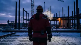 Bauarbeiter mit Milwaukee Heizjacke und M12-Akku am Gürtel auf einer frostigen Baustelle